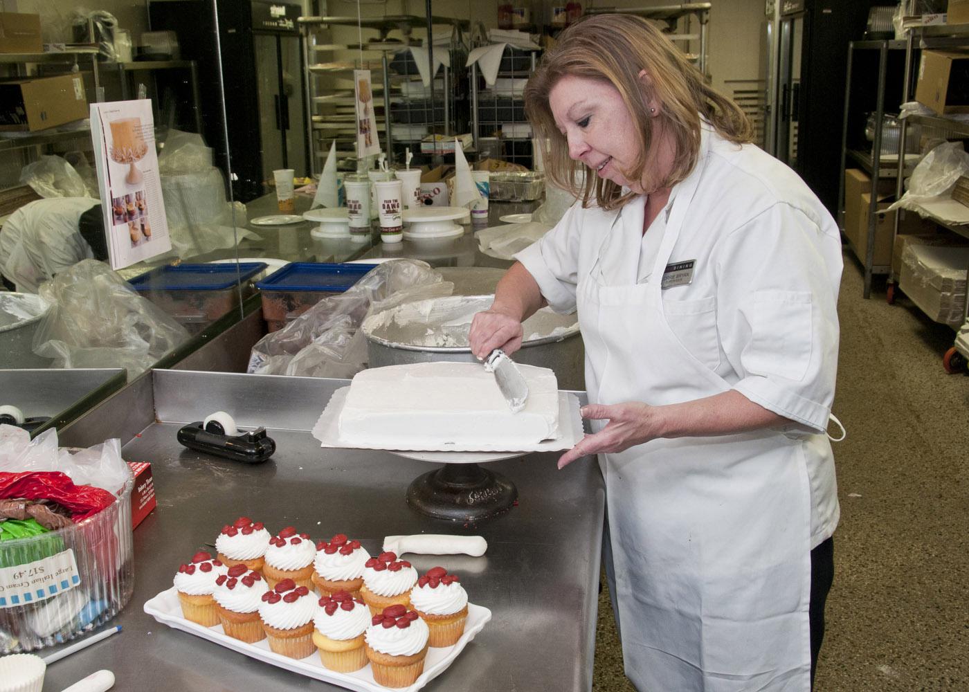 Lorrie Bryan, cake decorator at the Mississippi State University Fountain Bakery, creates Bully's pawprints to cupcakes after whipping up a batch of maroon frosting. (Photo by Scott Corey)