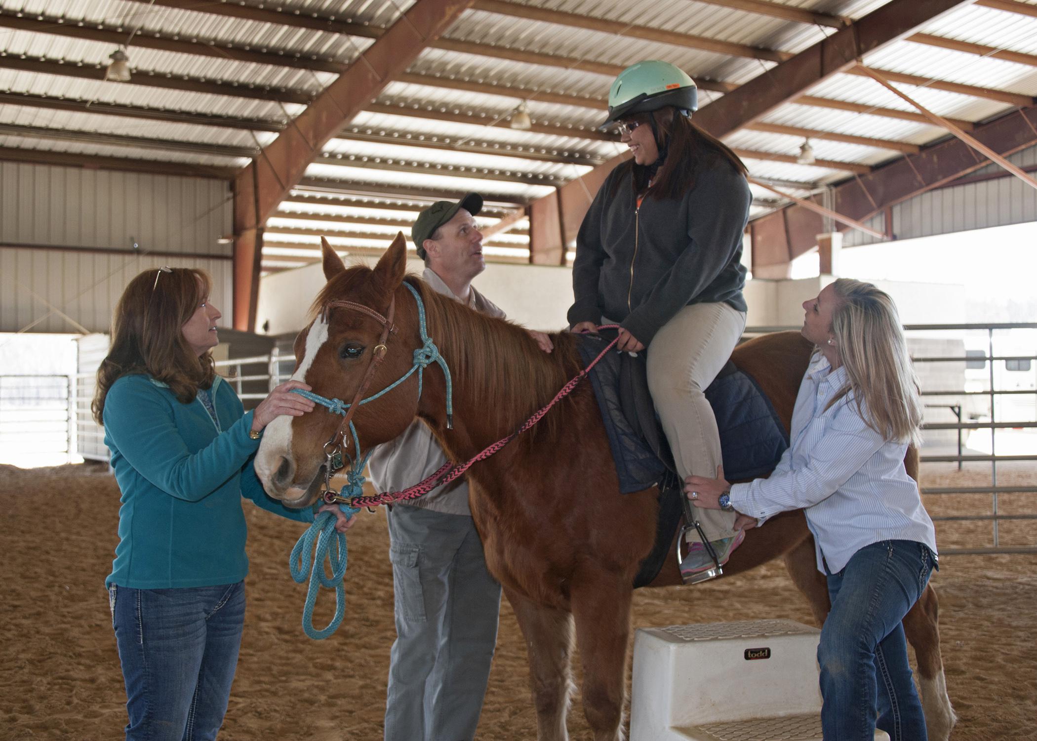 Lori Irvin, a therapeutic riding volunteer, holds the horse still while Mississippi State University Extension Service agents Jim McAdory and Cassie Brunson make sure Martina Tubby is comfortable for a ride at the Elizabeth A. Howard 4-H Therapeutic Riding and Activity Center in West Point on March 20, 2014. (Photo by MSU Ag Communications/Kat Lawrence)