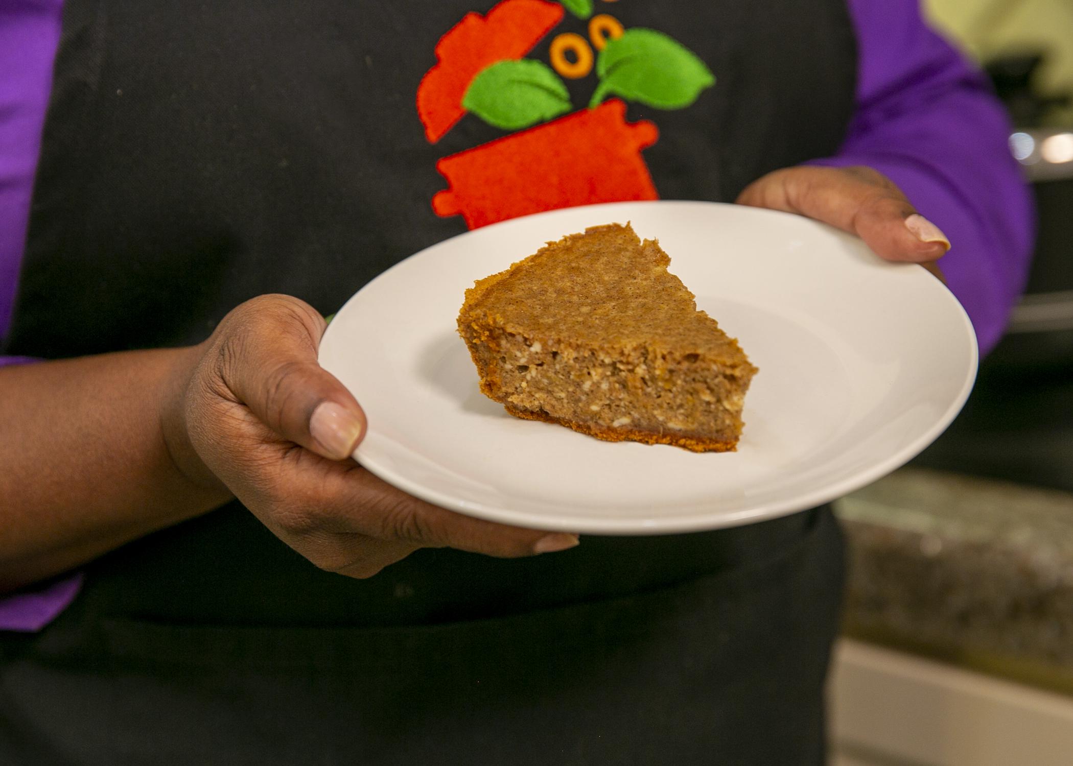 Hands hold a plate with a slice of sweet potato cheese pie