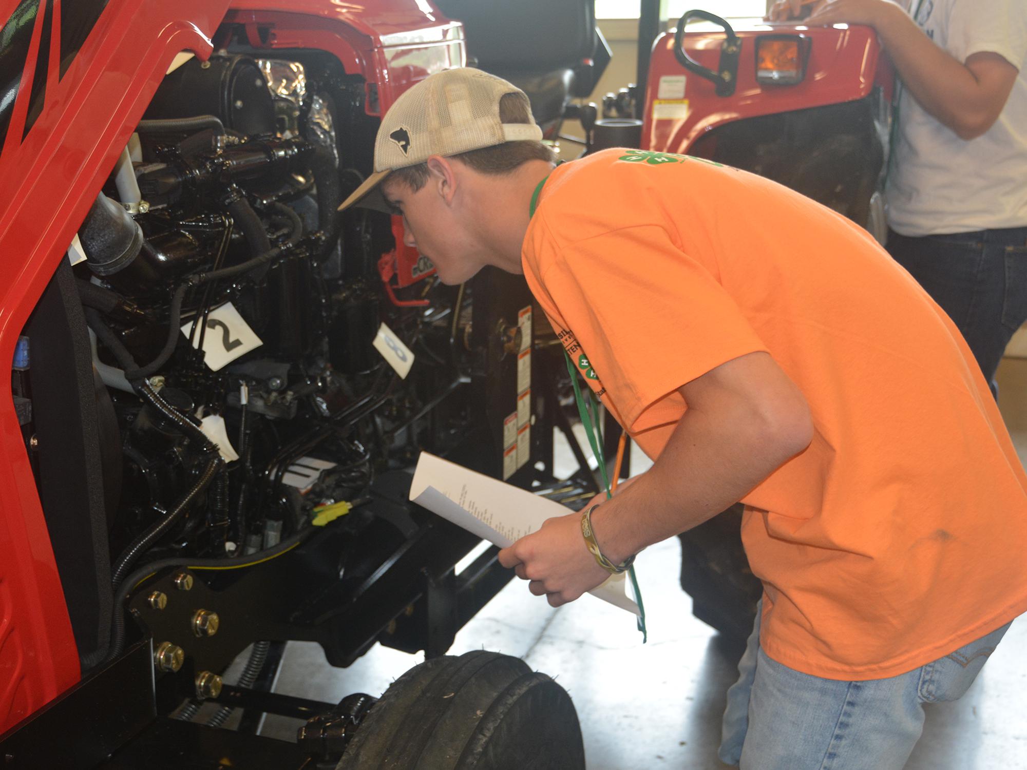 Rankin County 4-H member Robert Herrington takes a close look under the hood of a tractor as he identifies engine parts during a portion of the tractor competition on June 1, 2017. More than 700 4-H members took part in contests, workshops, tours and entertainment during their annual state meeting at Mississippi State University. (Photo by MSU Extension Service/Linda Breazeale)