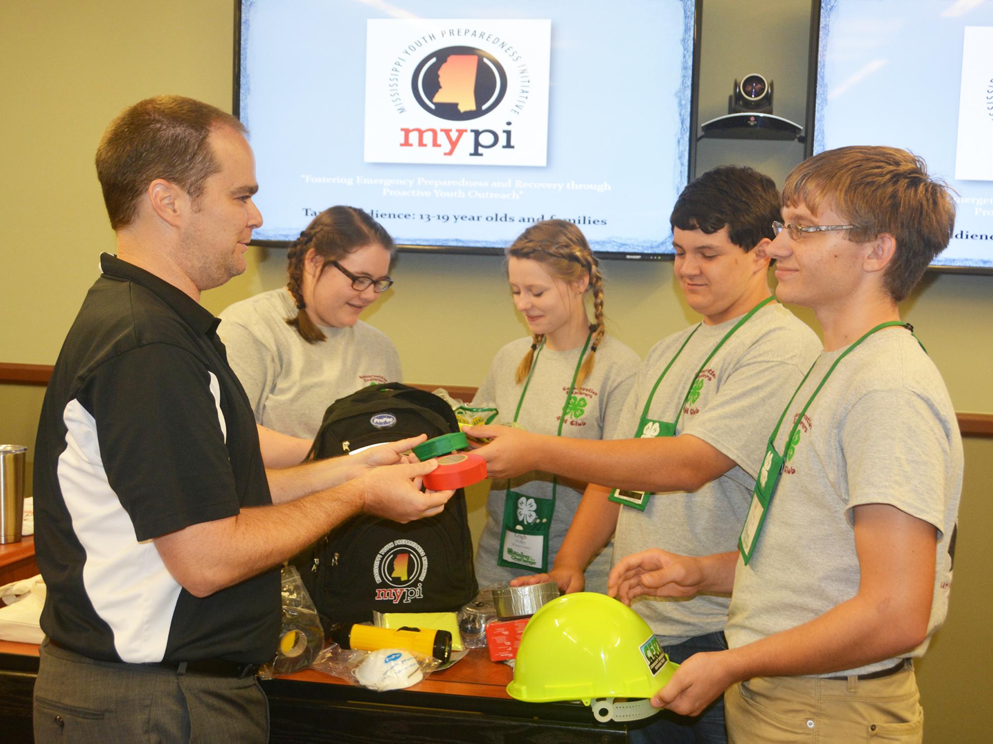 Ryan Akers (left), an assistant Extension professor in the Mississippi State University School of Human Sciences, helps 4-H members examine items in a disaster preparedness backpack. Madison Crawford (second from left) and Leigh Anne Walley, both of Greene County, joined Caleb Walley and Bo Henderson, both of Wayne County, in the workshop on June 1 at the 2017 State 4-H Congress in Starkville, Mississippi. (Photo by MSU Extension Service/Linda Breazeale)