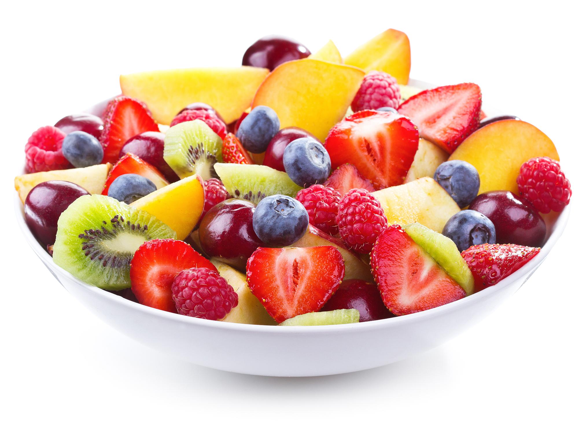 A white bowl of mixed chopped fresh fruits and berries on white background.