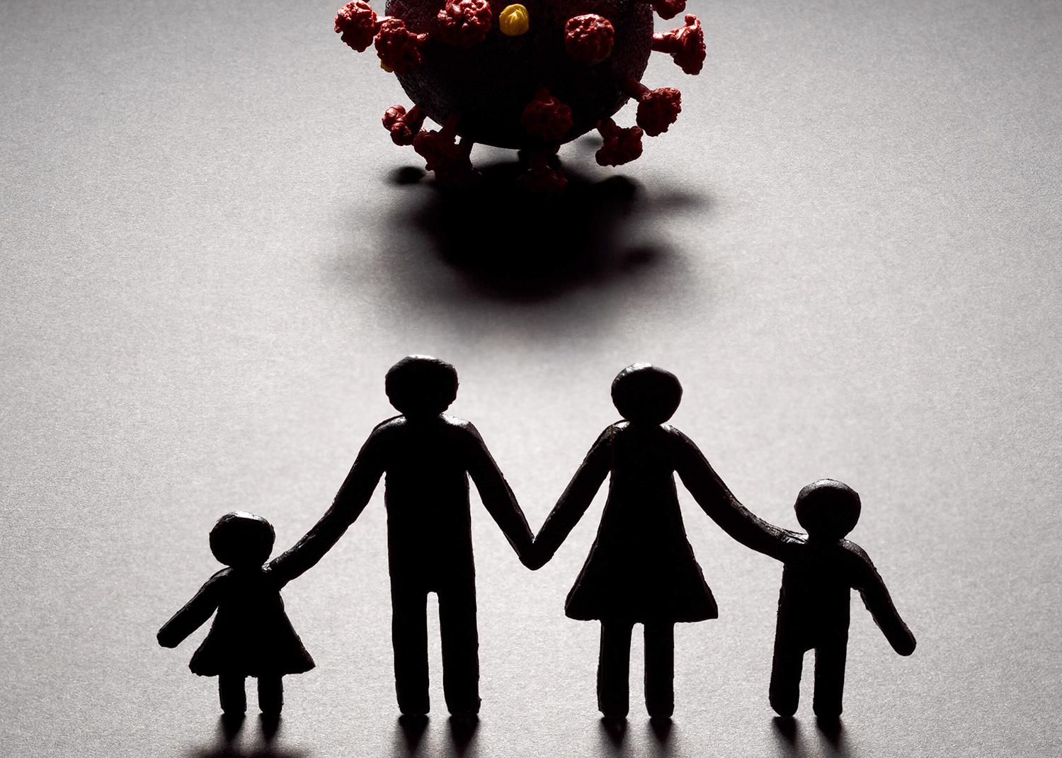Silhouette of a paper cut-out style family of four facing a three-dimensional model of the novel coronavirus. 