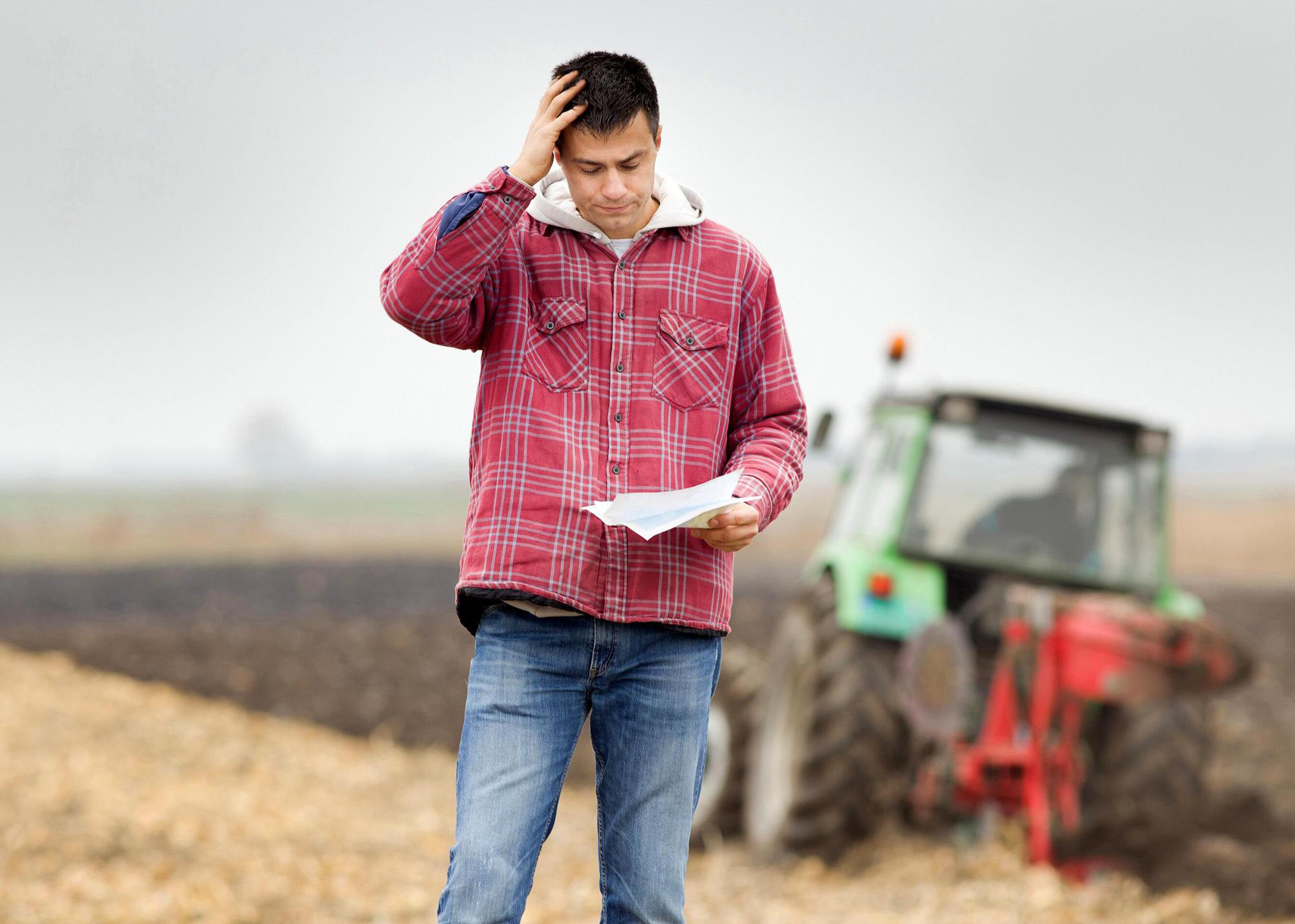 Man on a farm holding a baseball cap.