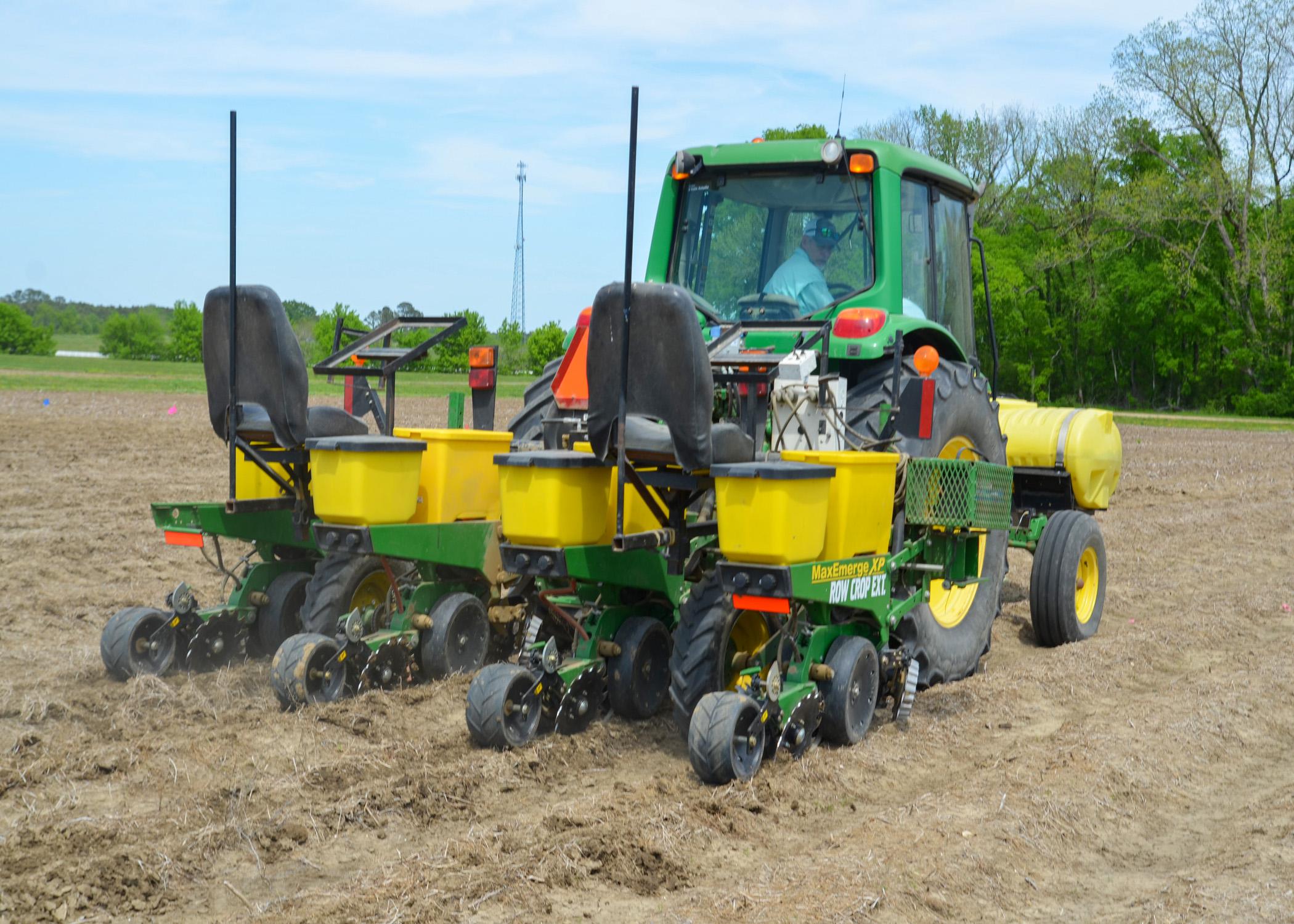 A man looks out the back window of a tractor in the field.