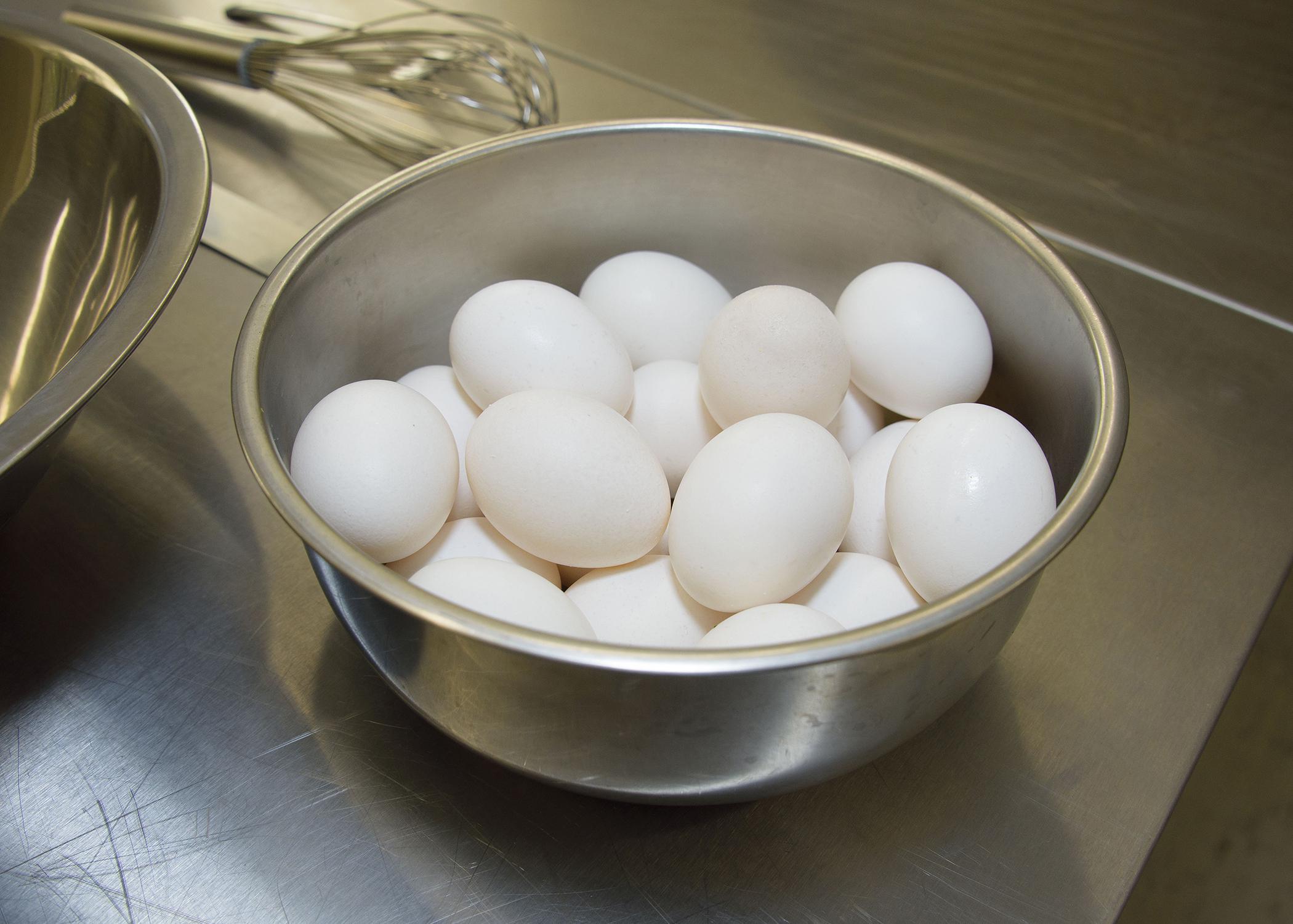 White eggs fill a metal bowl on a countertop.