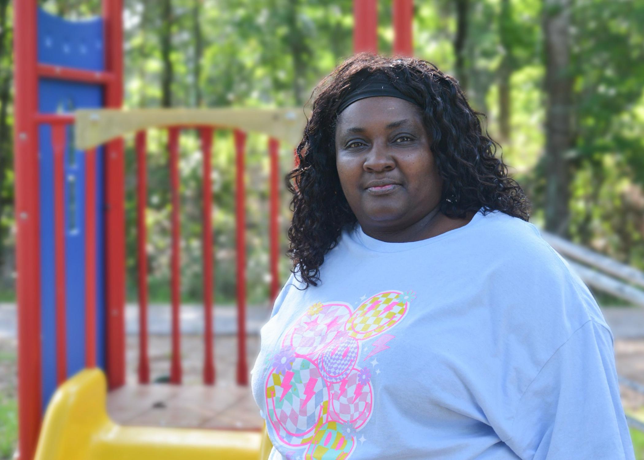 A woman stands outside in front of a playset.