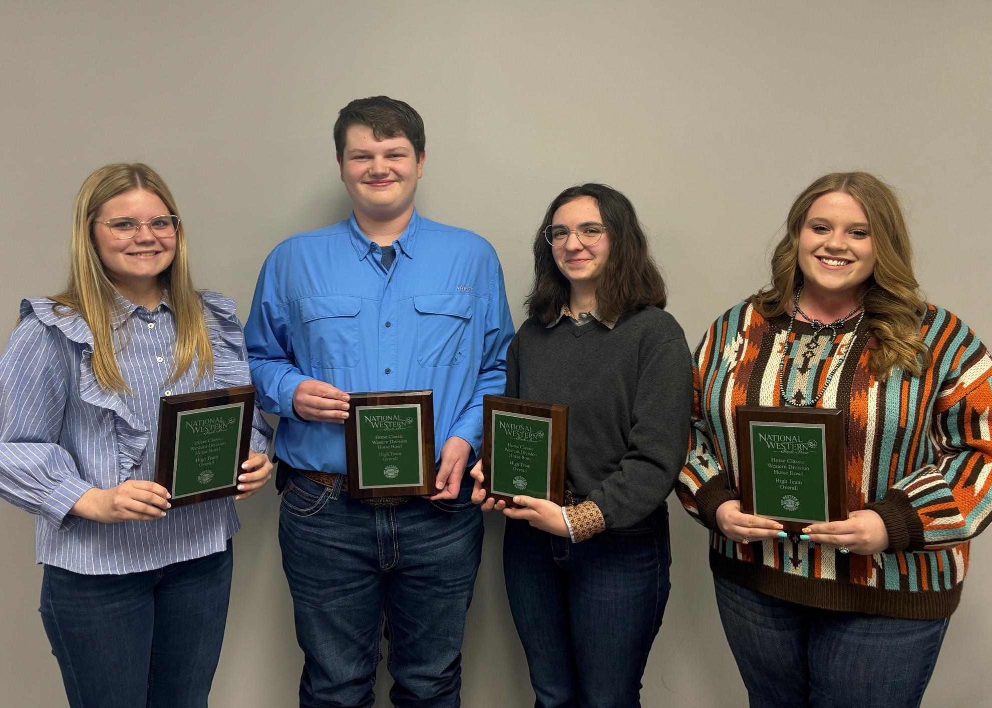 Four teenagers hold plaques.