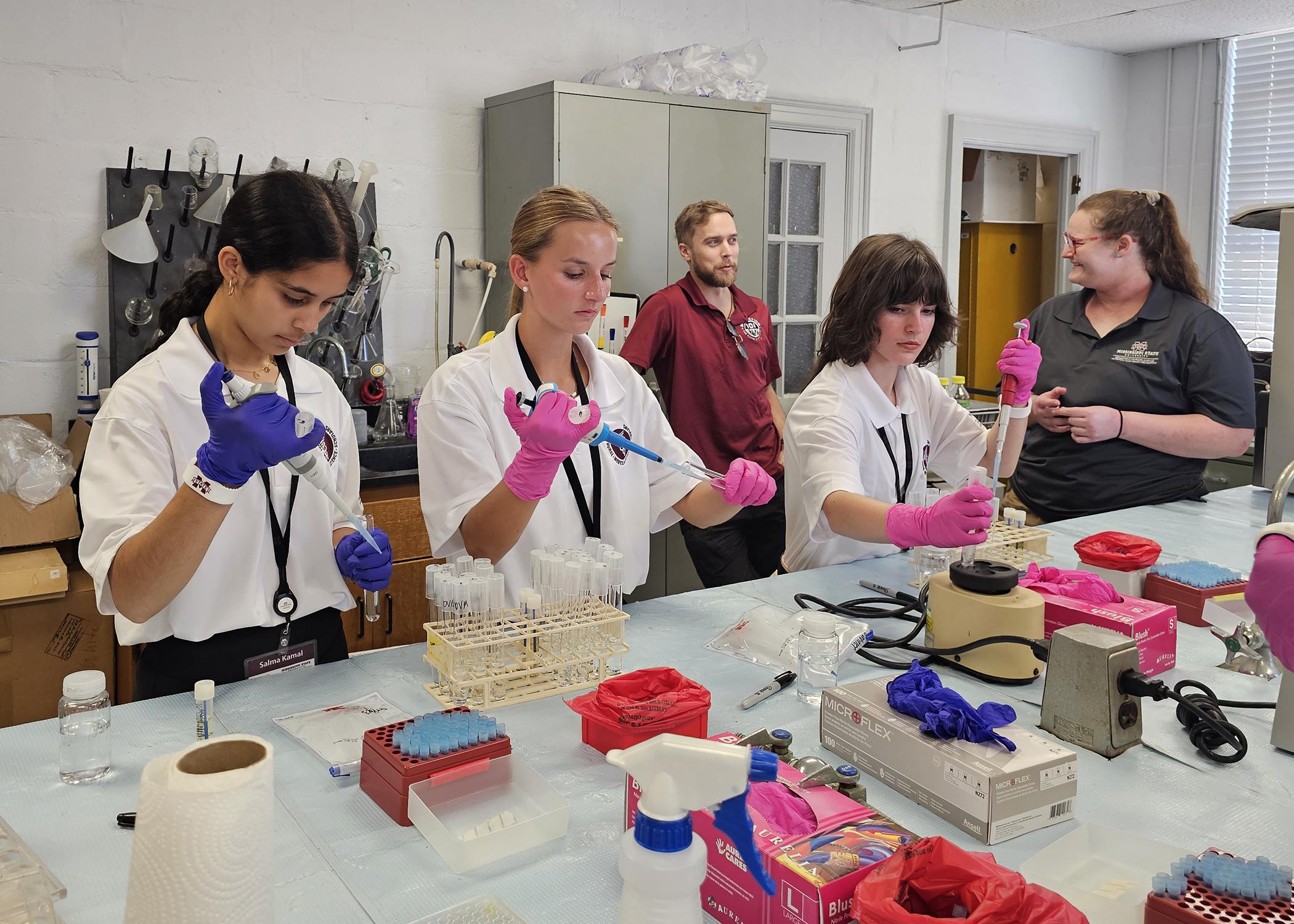 A group of young people use lab equipment in a classroom.