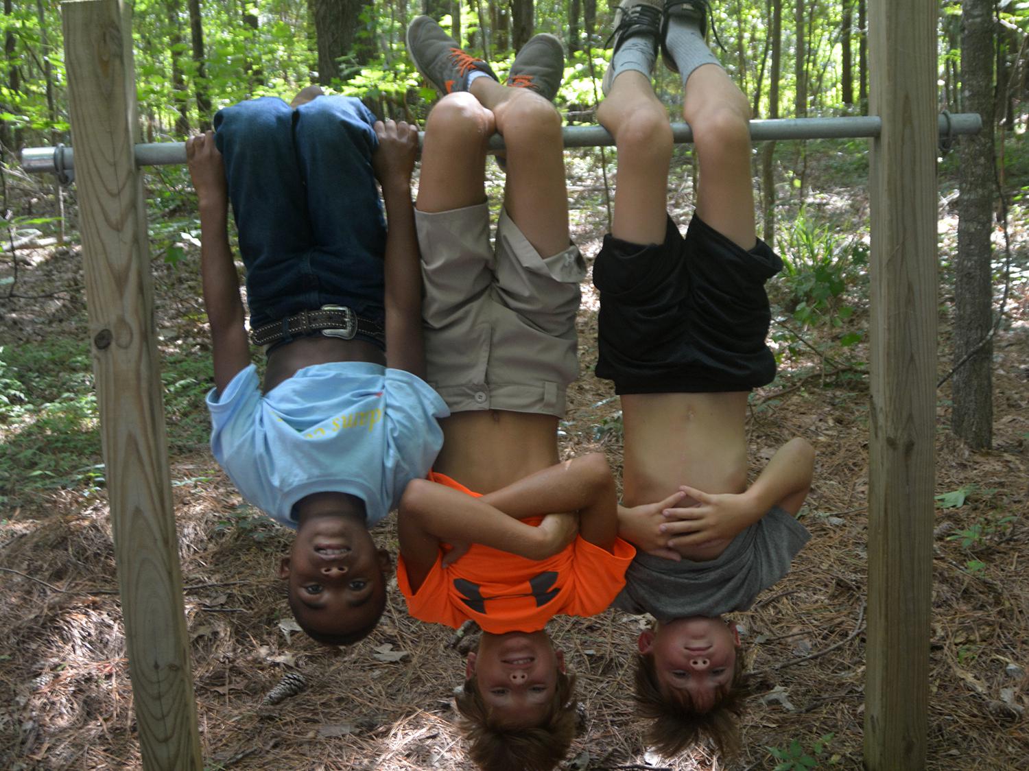 Imitating bats that like to hang upside down is a fun activity for children as they explore a nature trail at St. Catherine Creek National Wildlife Refuge near Natchez, Mississippi, on July 7, 2016. (Photo by MSU Extension Service/Linda Breazeale)