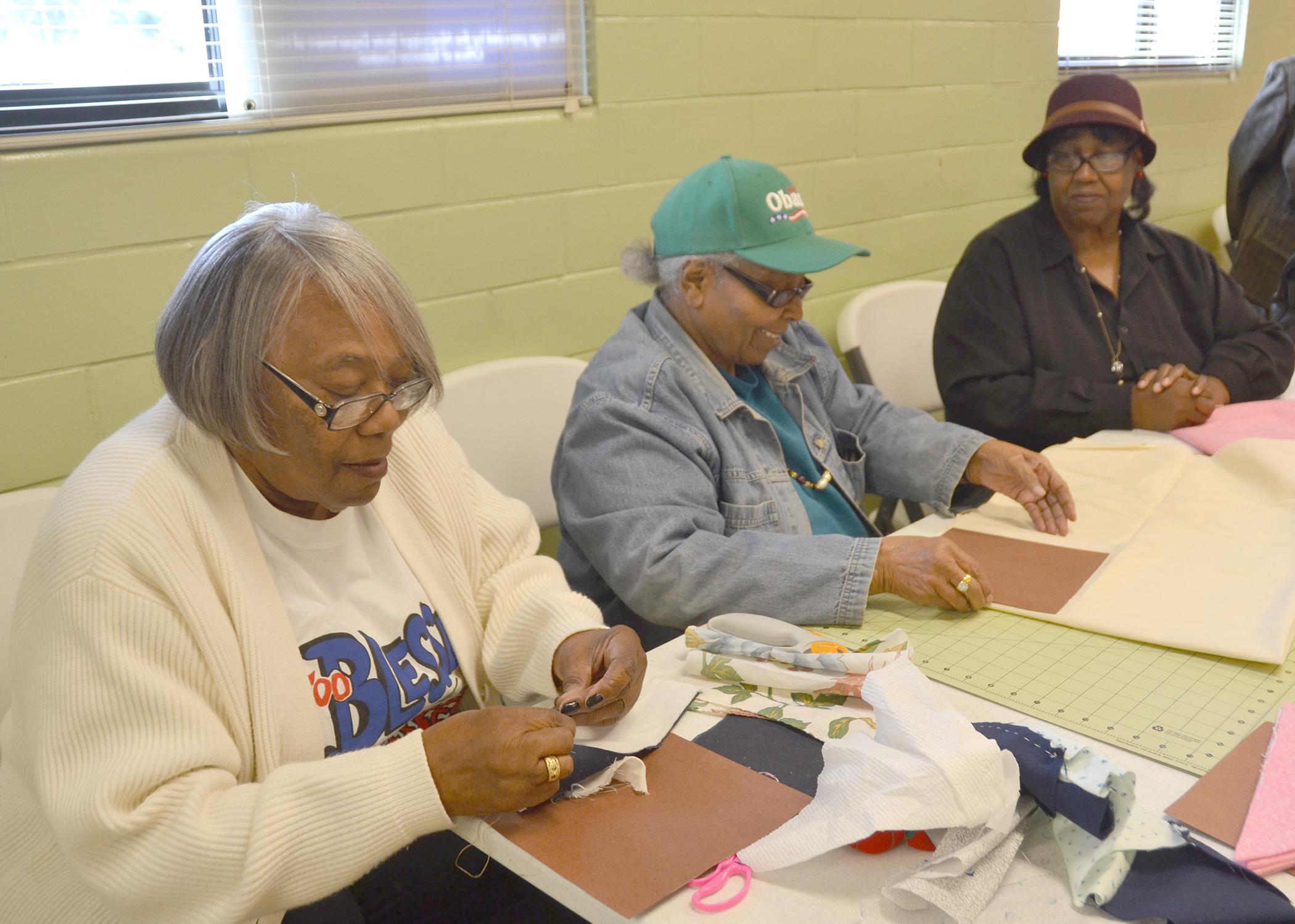 Annette Lockett, left, Thelma Washington and Mary Kohn, members of a newly formed Mississippi Homemaker Volunteers Club in Holmes County, cut out and sew quilt squares as part of a quilt-making project on Nov. 24, 2015. The group donated 67 lap quilts to residents at the Lexington Manor Senior Care facility. (Photo by MSU Ag Communications/Susan Collins-Smith)