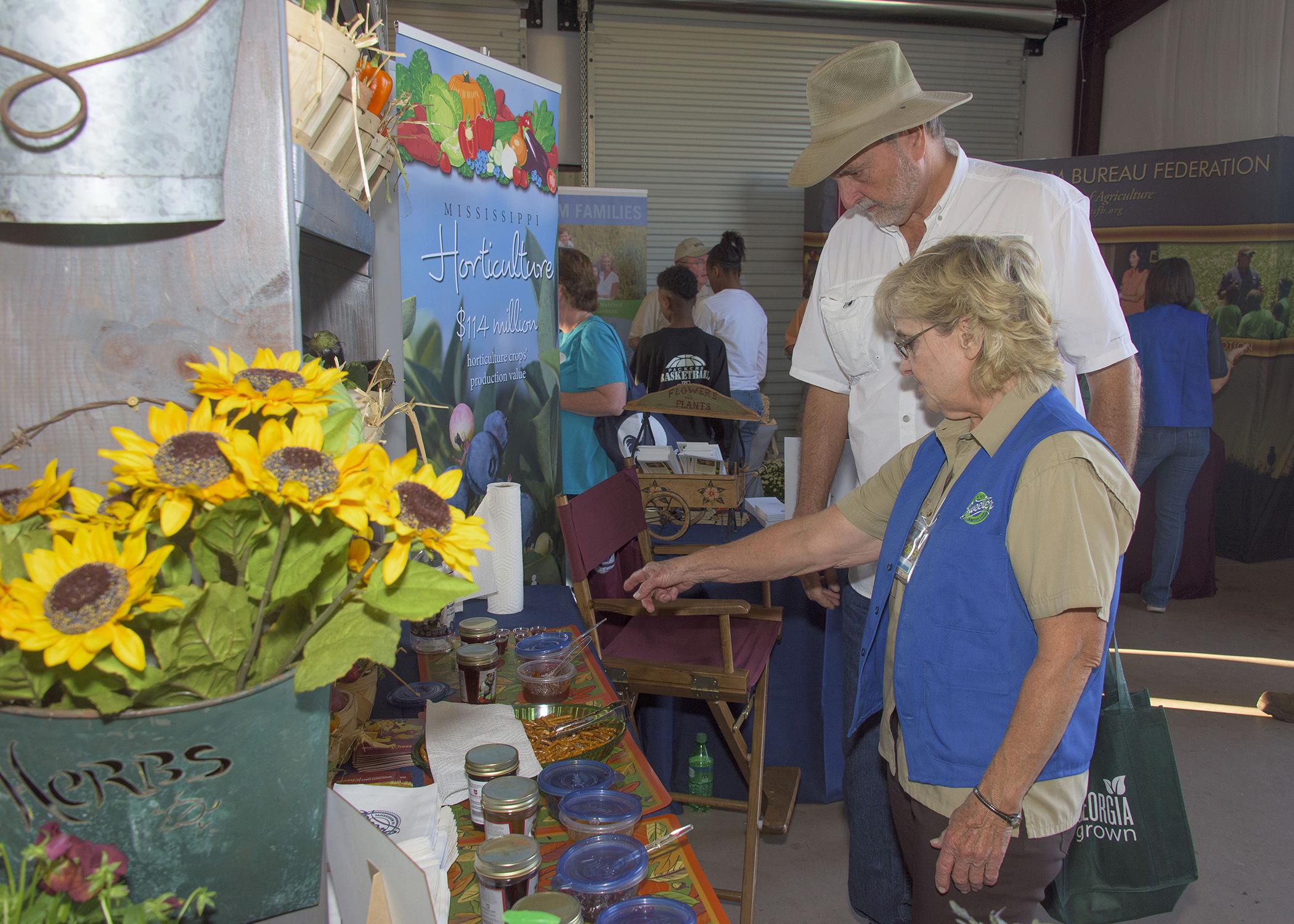 Lelia Kelly, a horticulture specialist with the Mississippi State University Extension Service, talks to a Sunbelt Ag Expo visitor about locally grown produce and Mississippi-made products on Oct. 22, 2015. (Photo by MSU Extension/Kevin Hudson)