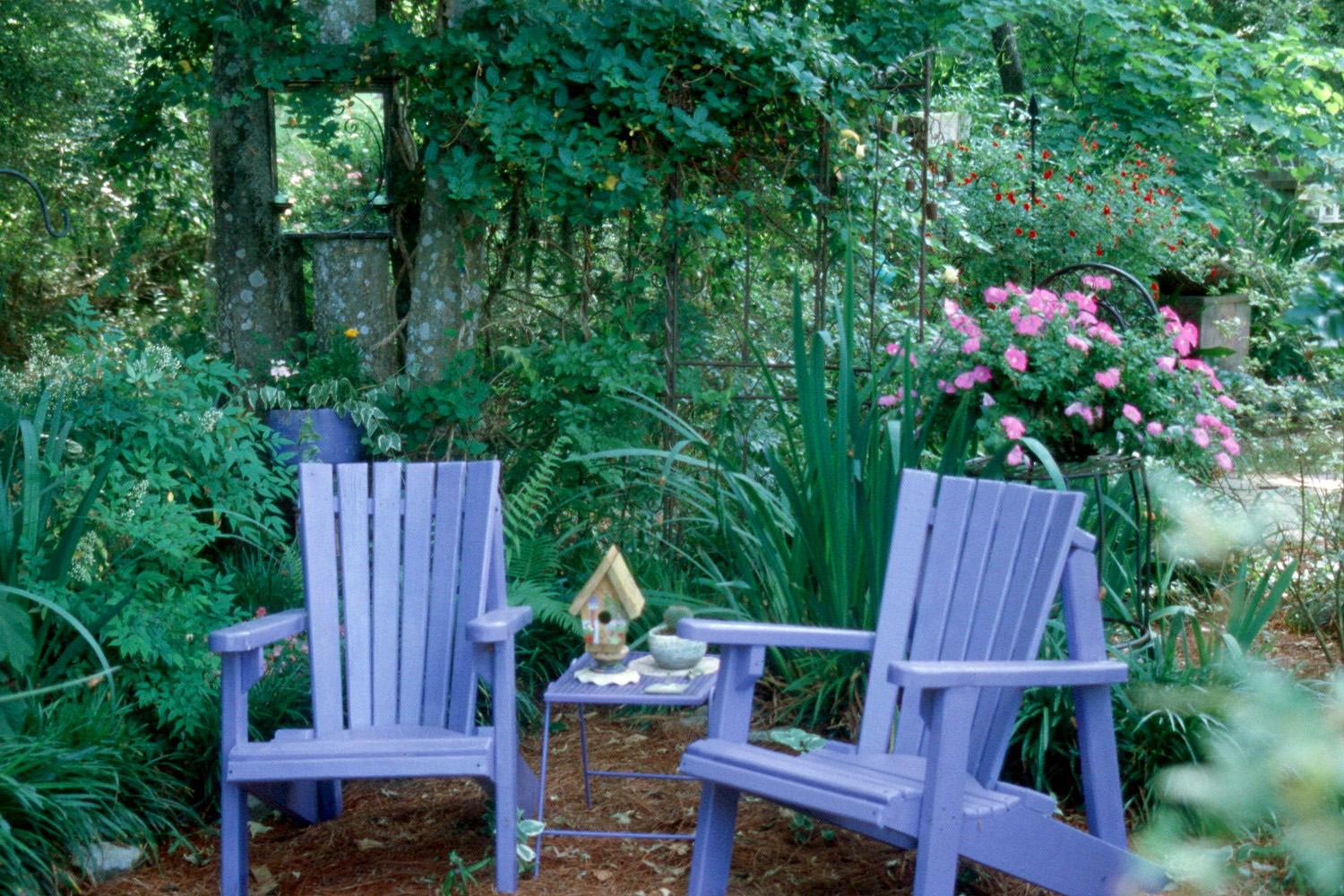 The mirror hanging on the tree over the left Adirondack chair blends comfortably into this lovely home-like setting.