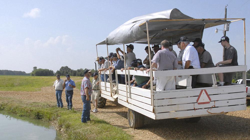 Okolona farmer Jay Schmidt explains his catfish farming techniques to a wagon-load of men from Virginia on July 29, 2010. The group also heard Schmidt explain farming practices related to corn, soybeans and truck crops. The Roanoke-Botetourt (Virginia) Farm Tour brought 40 men to learn about Mississippi agriculture. (Photo by Linda Breazeale)