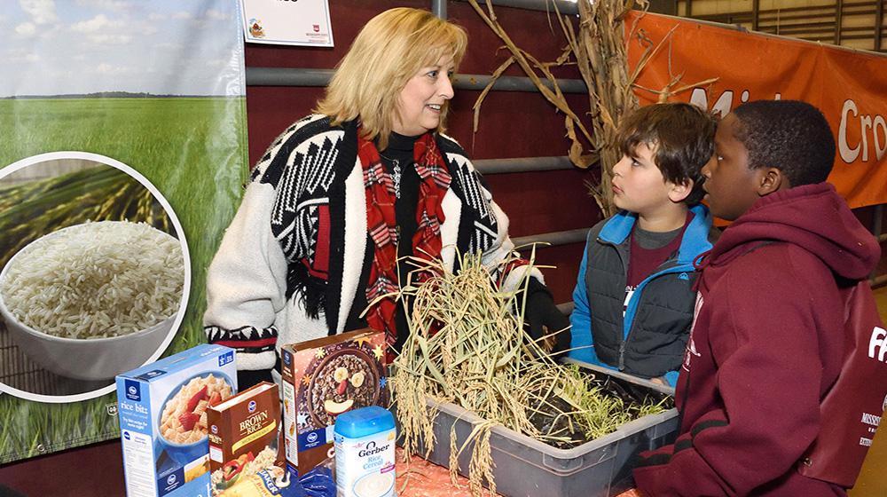 Lisa Stewart, an agent with the Mississippi State University Extension Service in Webster County, explains the importance of rice to Clayton Griffin and Jalen Washington, third-graders from Houston Upper Elementary School, at the FARMtastic event at the Mississippi Horse Park near Starkville on Nov. 13, 2014. (Photo by MSU Ag Communications/Kevin Hudson)