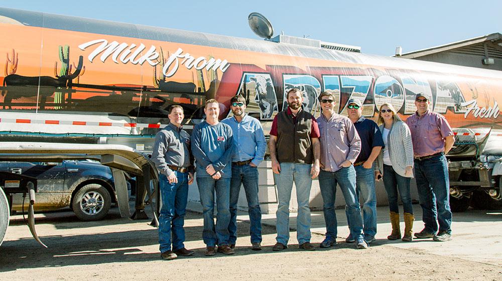 Group of people standing in front of Arizona dairy truck.