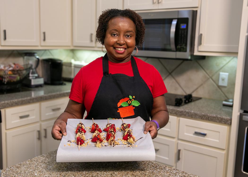 A woman holds a baking sheet of prepared Frozen Banana Splits