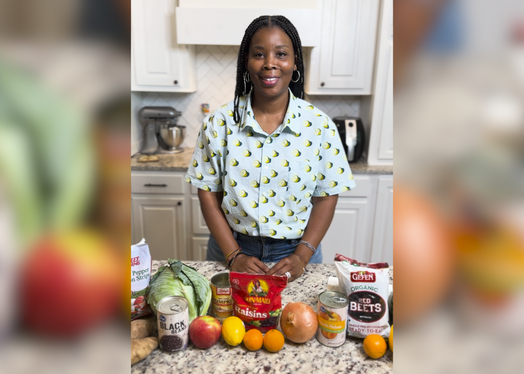 A woman in a kitchen with fruits and vegetables on the counter.