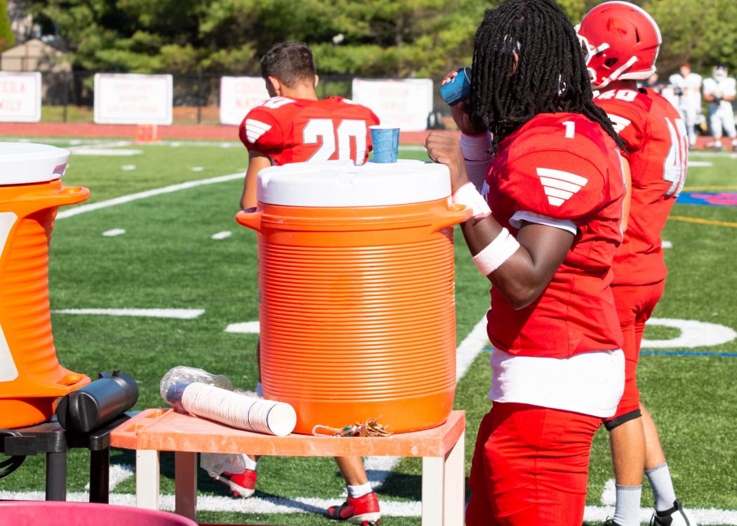 Football player getting water from a cooler.