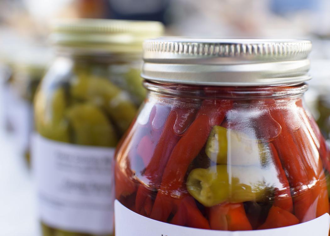 A glass jar with a metal lid is full of vegetables.