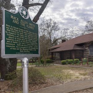 An historical marker about Mack Allen Smith and the Flames in front of the cabin-themed Carrollton Community House.