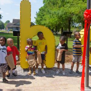 Children holding bags and standing among yellow letters.