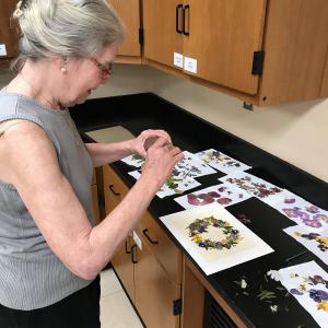 A woman creating a pressed floral picture.