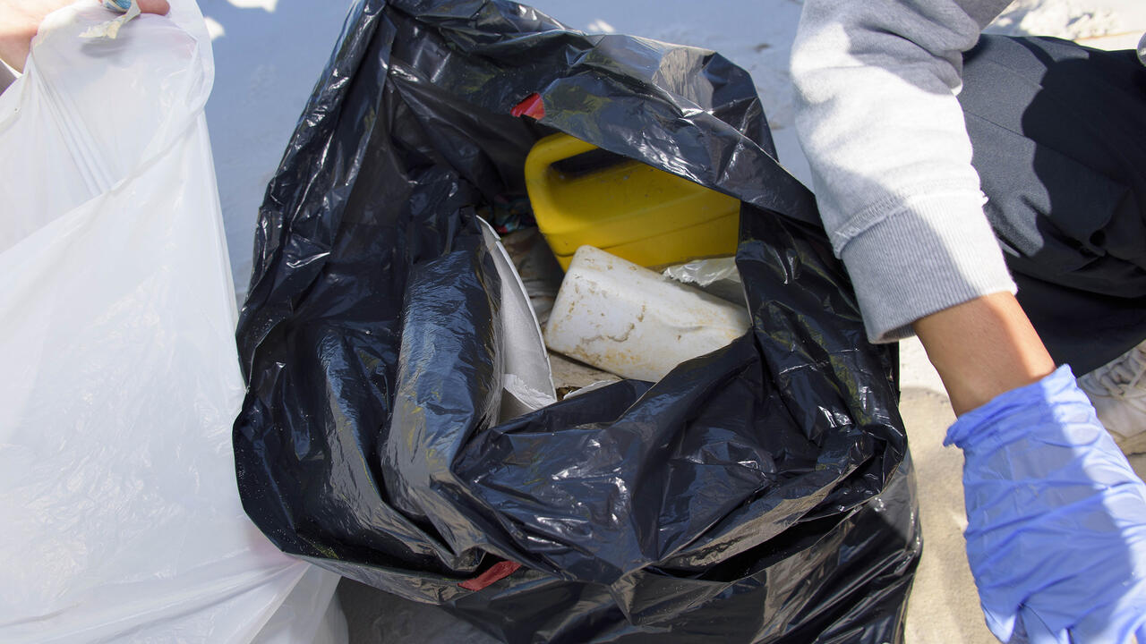 Plastic debris is seen in an open black trash bag sitting on the beach at the 2016 Mississippi Coastal Cleanup.