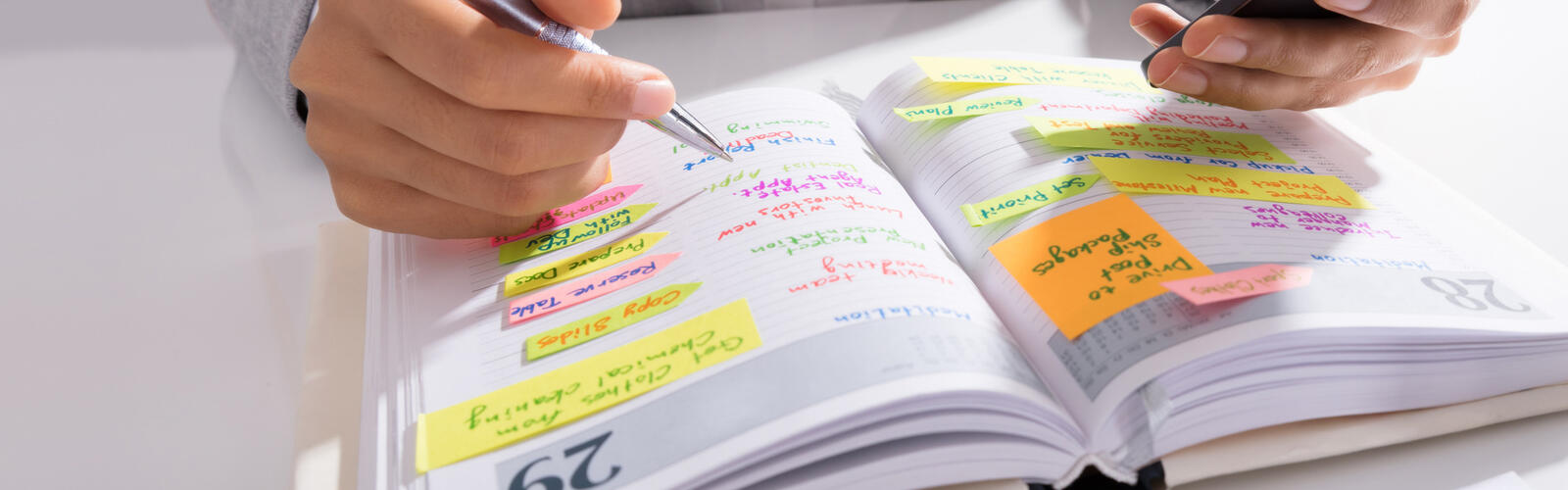 Person’s hands hold a mobile phone with a list of work on the desk.