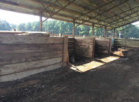 Two divided bins composed of lumber with an open top and front. The bins are covered by a roof above.