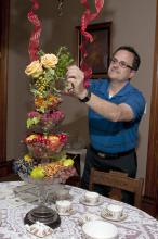 Jim DelPrince fills stacked glass comports with fruit, nuts and cut plant materials to create a stunning but inexpensive holiday centerpiece. (Photo by Scott Corey)