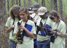Young women use hand-held GPS devices to mark the location of a red-cockaded woodpecker's nest. (Photos by Scott Corey)