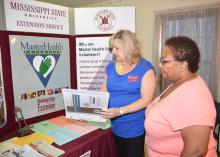 Mississippi State University Extension community health coordinator Ann Sansing reviews some of the Master Health Volunteer educational material with Annie Williams at the one-year anniversary celebration of the John Wesley Health Education Center in Durant, Mississippi, on July 25, 2014. (Photo by MSU Ag Communications/Linda Breazeale)