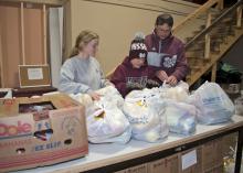 Holiday giving opportunities are an excellent time for parents to model generosity for their children. On Nov. 13, 2014, Mississippi State University student Heather Dodd, left, of Winona, prepares bags of groceries to be distributed to charity along with Latham Blake and his father, John Blake of Starkville. (Photo by MSU Ag Communications/Kat Lawrence)