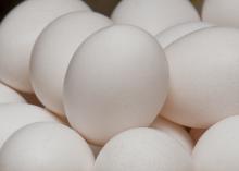 A close up of white eggs stacked in a bowl with other white eggs.