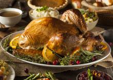 A roasted turkey and side dishes fill a table set for a meal.