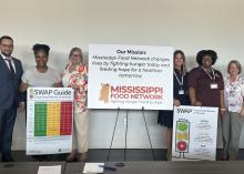Two groups of three people, with each group holding a research poster and a poster promoting the Mississippi Food Network propped between the two groups.
