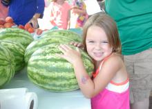 Emily Grace Barnette is ready to take this watermelon home from the Starkville Community Market on June 21, 2016. (Photo by MSU Extension Service/Linda Breazeale)