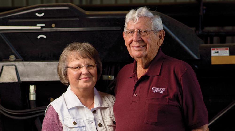 A man and woman stand next to each other smiling.