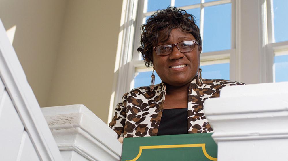 A woman standing behind a green sign that reads "Oktibbeha County 4-H."