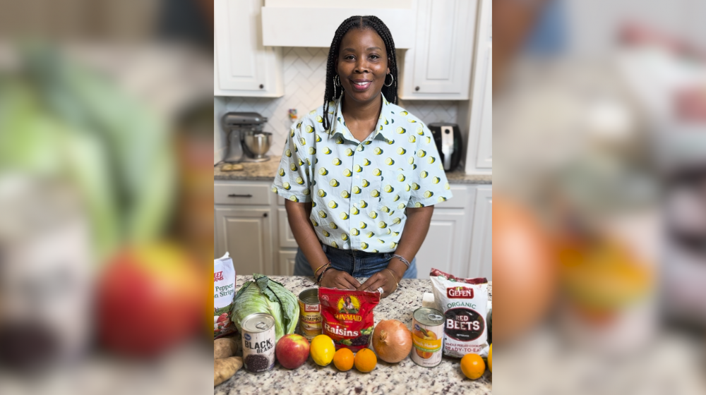 A woman in a kitchen with fruits and vegetables on the counter.