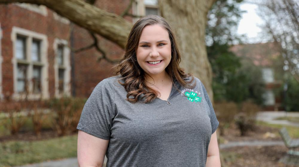 A standing woman smiling and wearing a Tennessee 4-H polo.