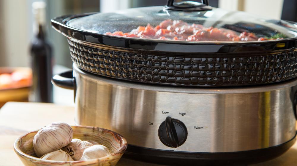 A slow cooker filled with a meal sits on a counter.