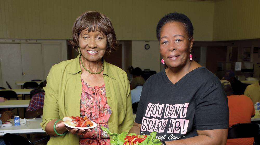 Two elderly women display their healthy food choices.