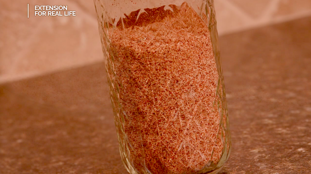 A pint glass jar filled with homemade taco seasoning sits on a kitchen countertop.