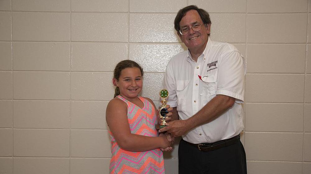 A 4-H member receiving an award from a Mississippi State University Extension Service agent.