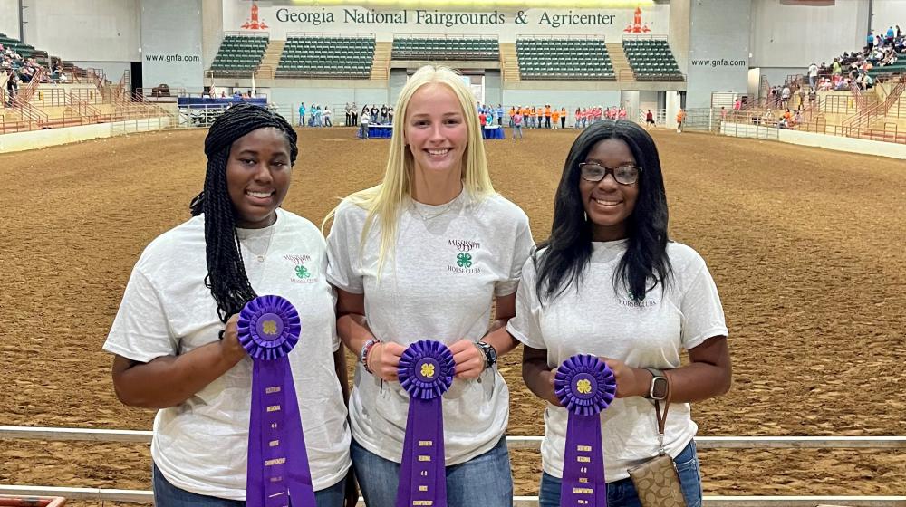 Group of three young ladies holding seventh place ribbon from horse club event