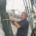 Marine resources specialist Dave Burrage  installs a bycatch reductions device into a shrimp net.