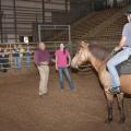 Anthony Busacca, a master's level instructor with the North American Riding for the Handicapped Association, teaches Hannah Miller, standing, and Natalie Clark Langston methods for effective and safe therapy sessions. (Photo by Scott Corey)