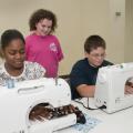 Calhoun County youth have an opportunity to learn the art of sewing through a new 4-H club named "A Stitch in Time." Operating the new computerized sewing machines donated by Singer Co. and "Heirlooms Forever" of Tupelo are, from left, Keyonia McGuirt of Pittsboro and Taylor Liles of Calhoun City. Observing is Hannah Long of Calhoun City. (Photo by Scott Corey)